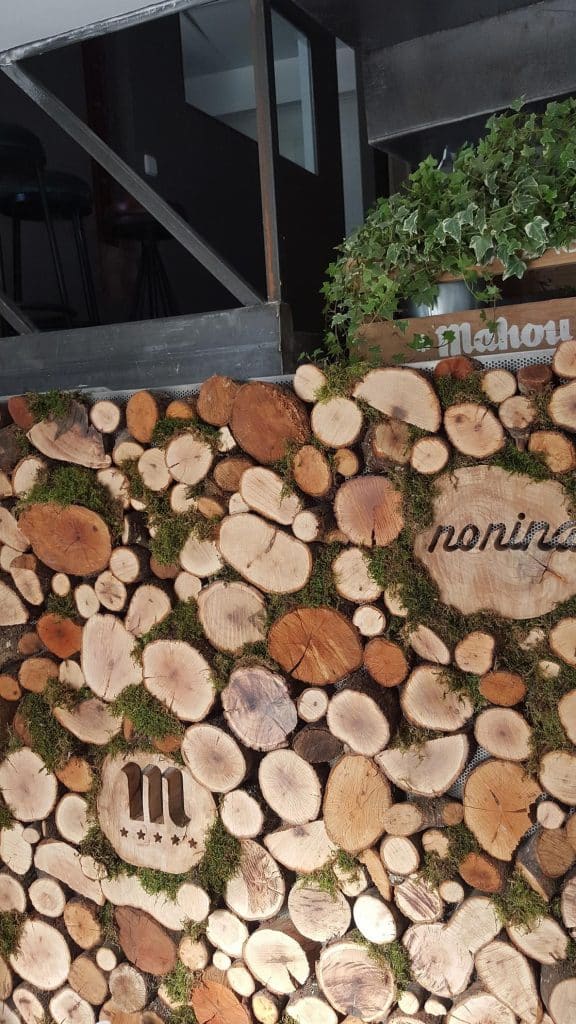 Pared de rodajas de tronco con el logotipo del restaurante Noníná
