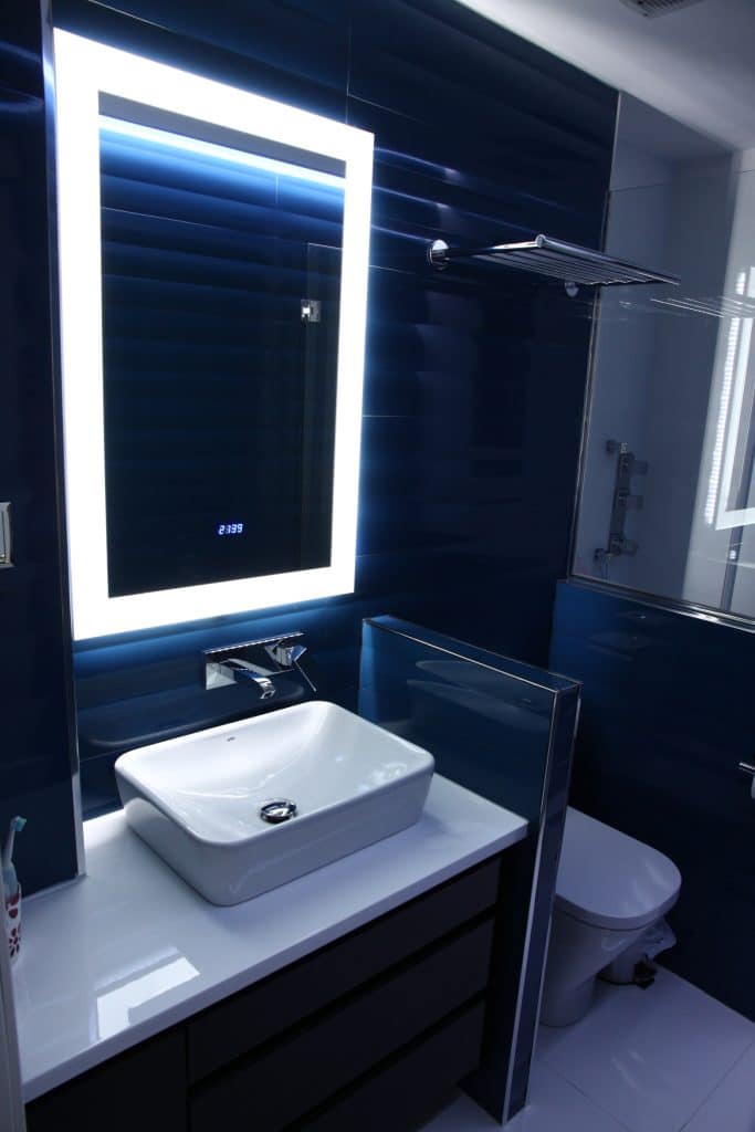 Lavabo de apoyo con espejo retroiluminado y azulejo azul en el baño de Collado Villalba