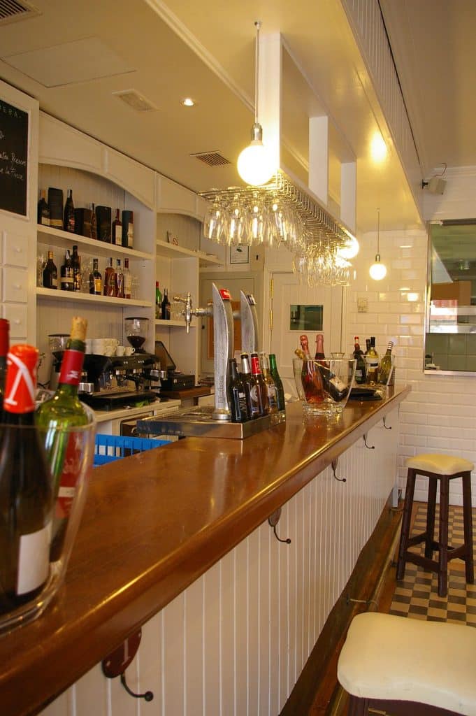 Barra larga de madera con frente de friso blanco en la Gastroteca al Alba de Majadahonda