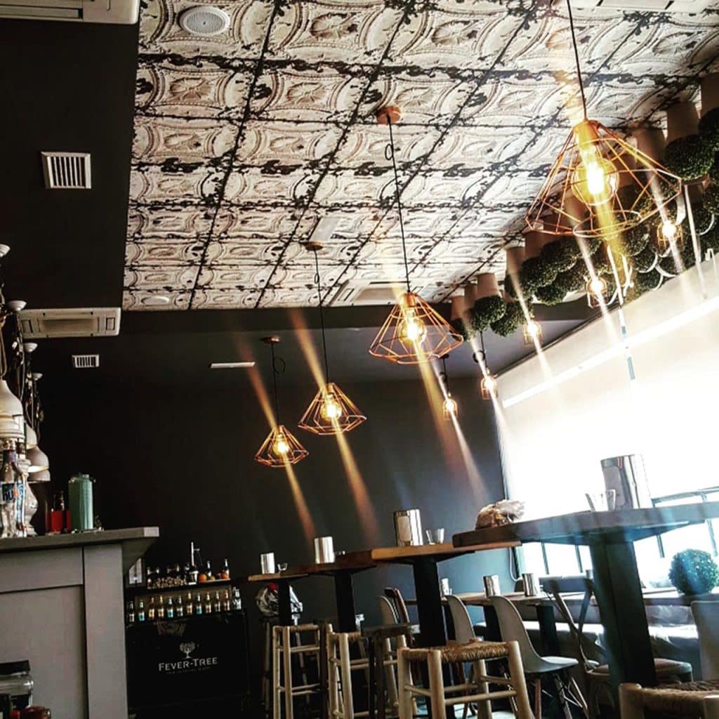 Barra del restaurante Buenos Días Princesa con techo de placas decorativas y lámparas de hilo