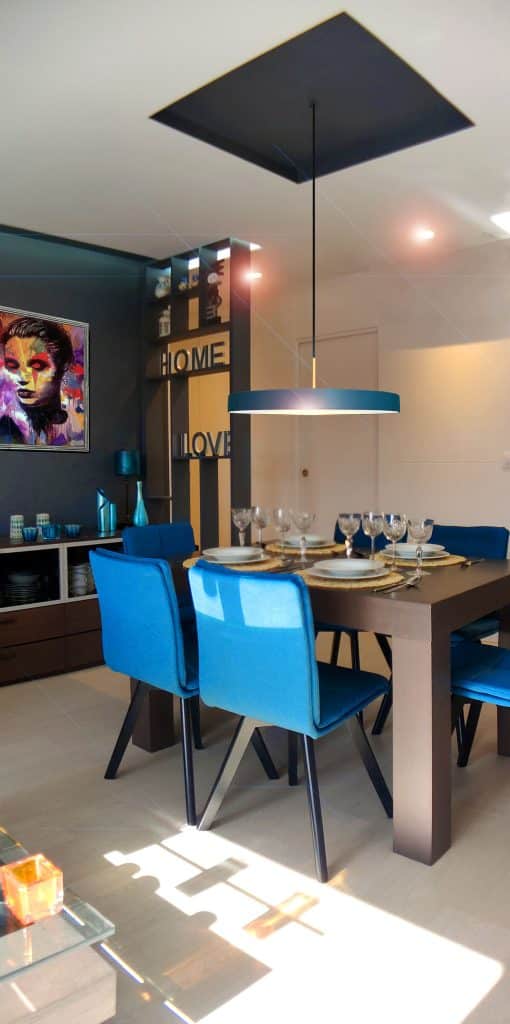 Comedor con sillas azules y lámpara colgante en el apartamento de Moratalaz