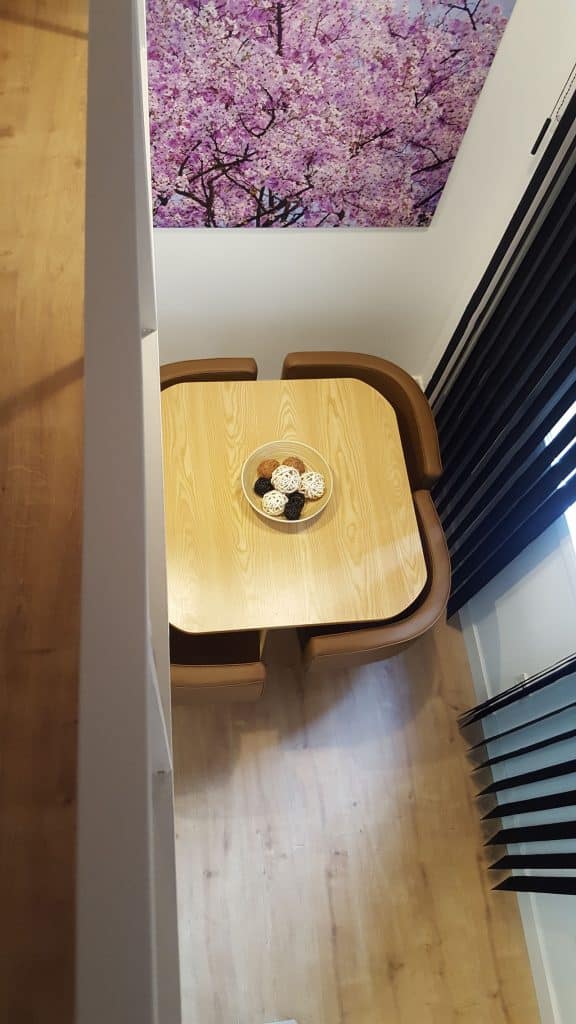 Rincón con mesa de madera bajo un techo con fotografía de cerezos en el apartamento de Tetuán