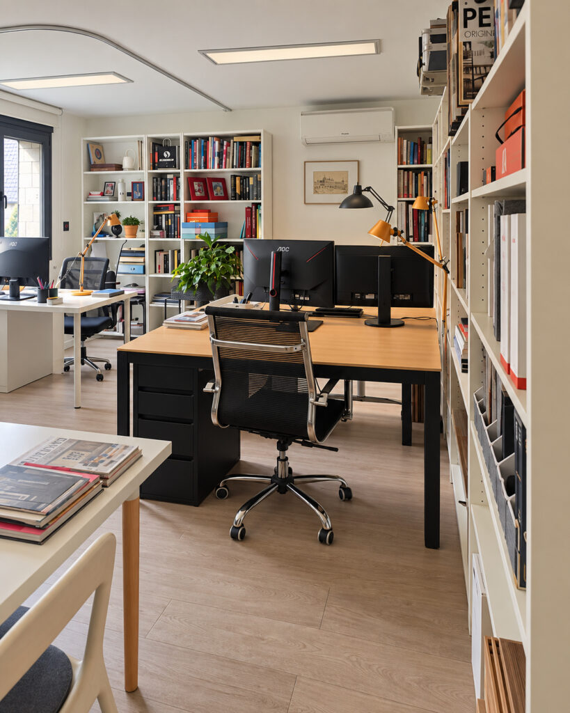 Mesa de trabajo del estudio con biblioteca de suelo a techo en la casa-estudio de Las Matas