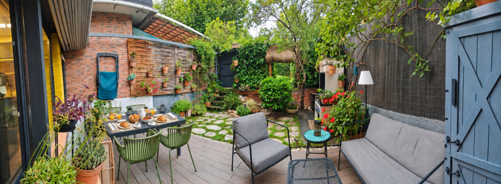 Jardín trasero con zona de comedor y vegetación en la casa-estudio de Las Matas