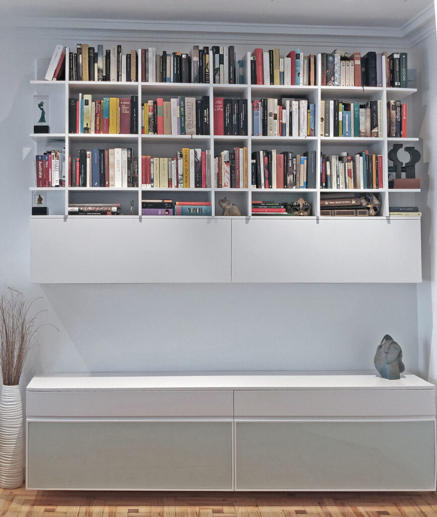 Librería blanca de pared a techo sobre mueble bajo lacado en el salón del apartamento de José Abascal