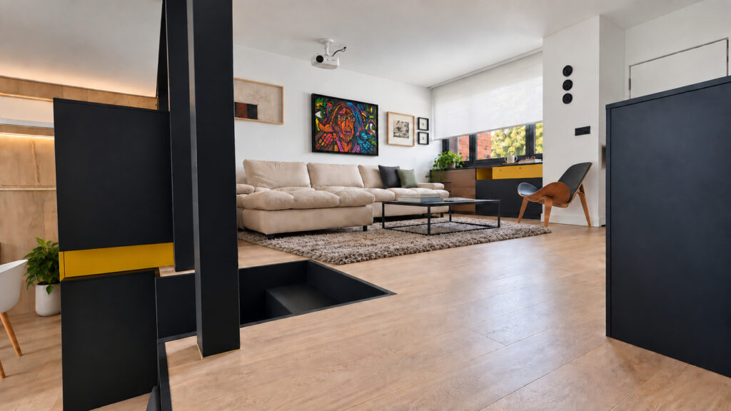 Salón visto desde la escalera con pilar negro y sofá claro en la casa-estudio de Las Matas